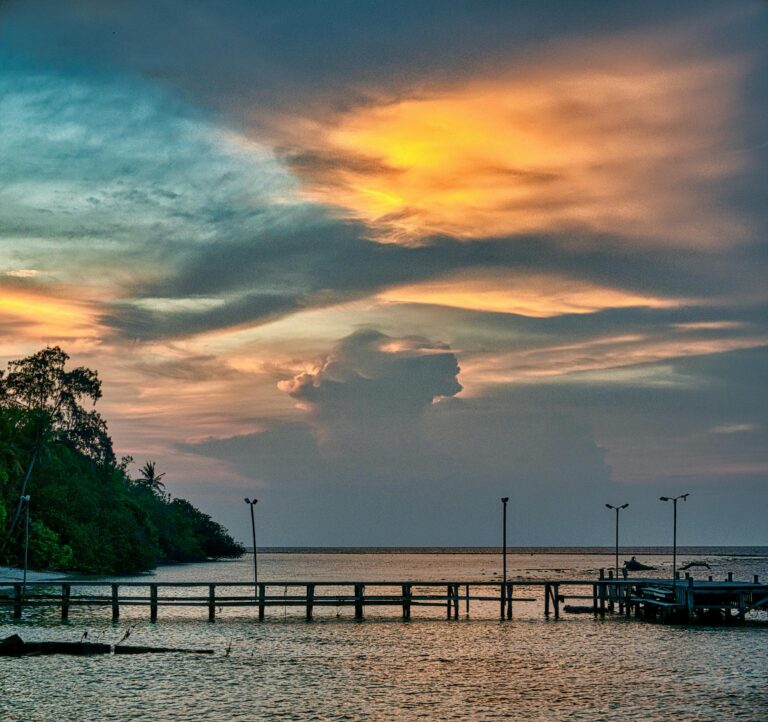 A tranquil sunset view with a jetty in Jakarta, Indonesia, showcasing vibrant skies and calm waters.