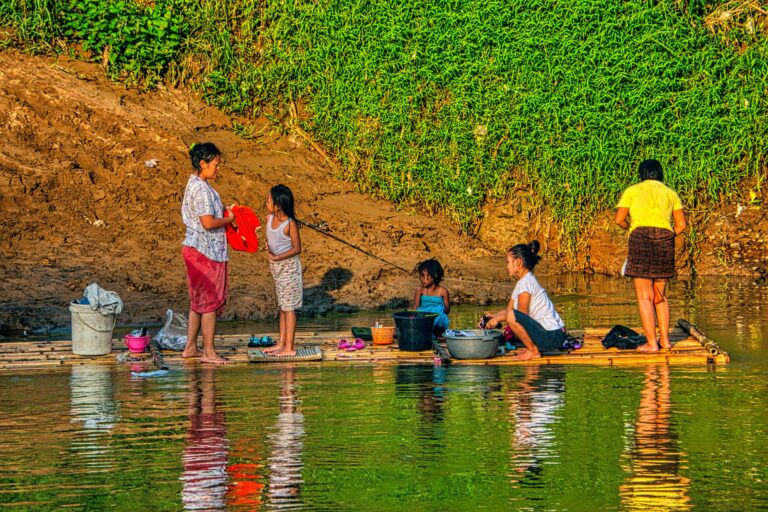 Family washing clothes on a bamboo raft in Gunung Sindur River, Indonesia.